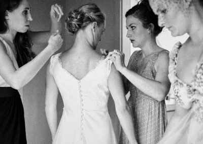Brautjungfern schließen beim Getting Ready das Brautkleid, schwarzweiß