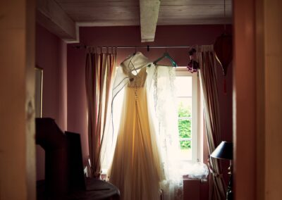 Brautkleid hängt am Fenster eines Zimmers im Gegenlicht – Hochzeit in Hamburg