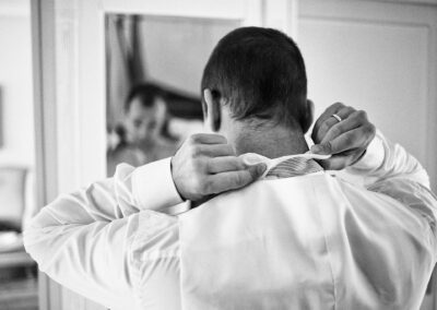 Bräutigam knöpft sich beim Ankleiden den Kragen zu, Rückansicht – Hochzeit in Hamburg