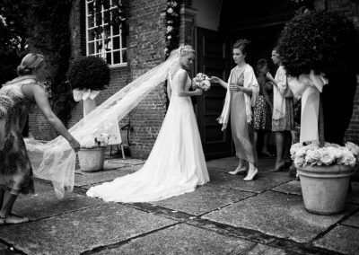 Braut wird vor der Kirche der Schleier gerichtet, schwarzweiß – Hochzeit in Hamburg