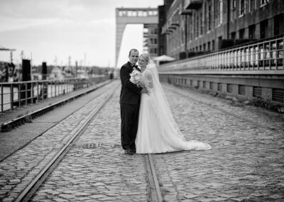 Brautpaar auf einer gepflasterten Kaimauer am Hafen – Hochzeit in Hamburg