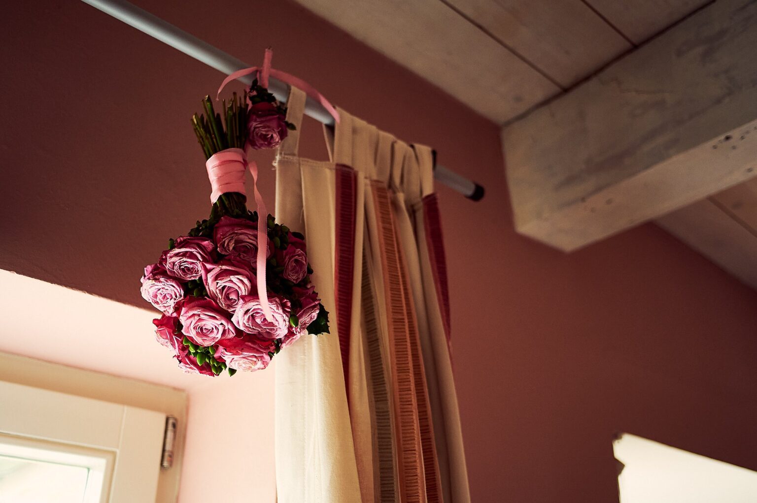 Brautstrauß aus Rosen hängt in einem rosa Zimmer am Fenster – Hochzeit in Hamburg