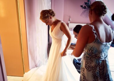 Braut wird beim Ankleiden geholfen, im weichen Fensterlicht – Hochzeit in Hamburg