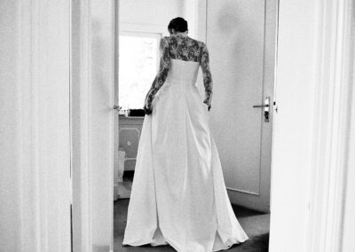 Braut im Spitzenkleid tritt durch eine Tür, Rückansicht, schwarzweiß – Hochzeit in Hamburg