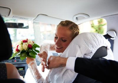 Braut wird im Auto umarmt, den Brautstrauß in der Hand – Hochzeit in Hamburg
