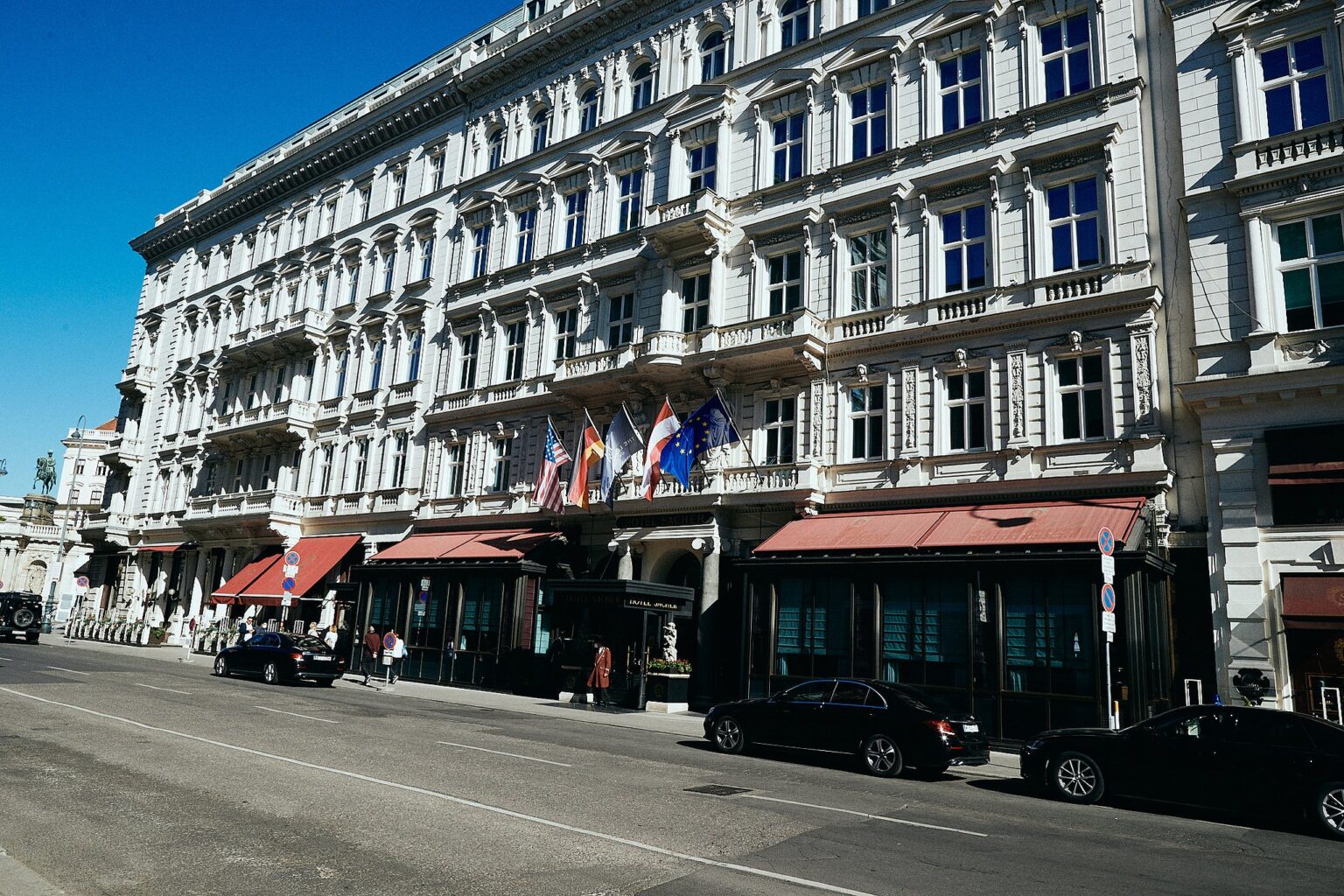 Hotelfassade mit roten Markisen in der Wiener Innenstadt unter blauem Himmel – Hochzeit in Wien