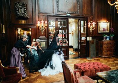Braut im schwarzen Kleid mit Gästen in einem holzvertäfelten Salon mit Kronleuchtern – Hochzeit in Wien