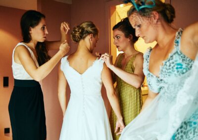 Brautjungfern schließen beim Getting Ready das Brautkleid