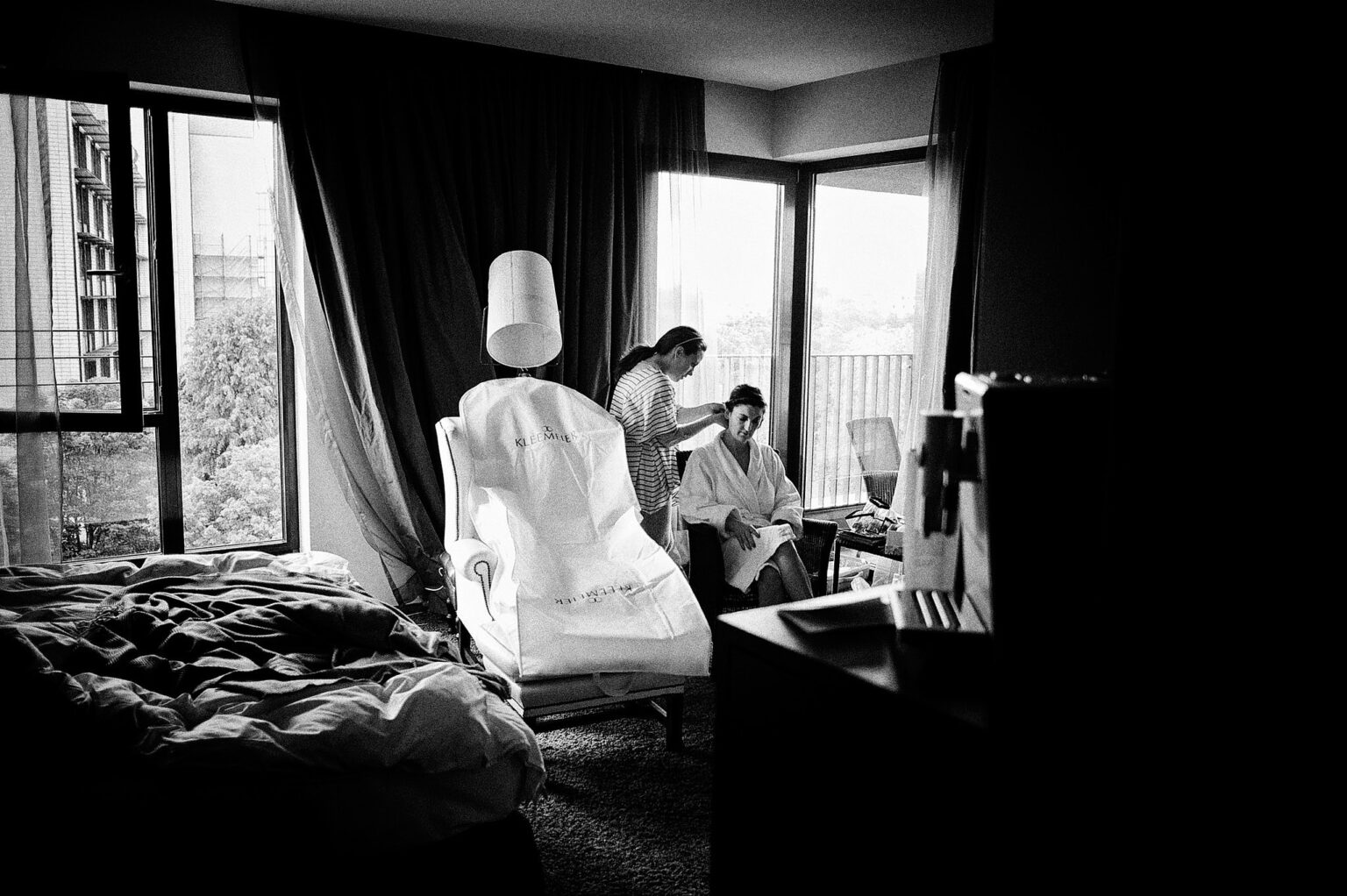 Hotelzimmer mit Brautkleid auf einem Stuhl am Fenster, schwarzweiß – Hochzeit in Hamburg