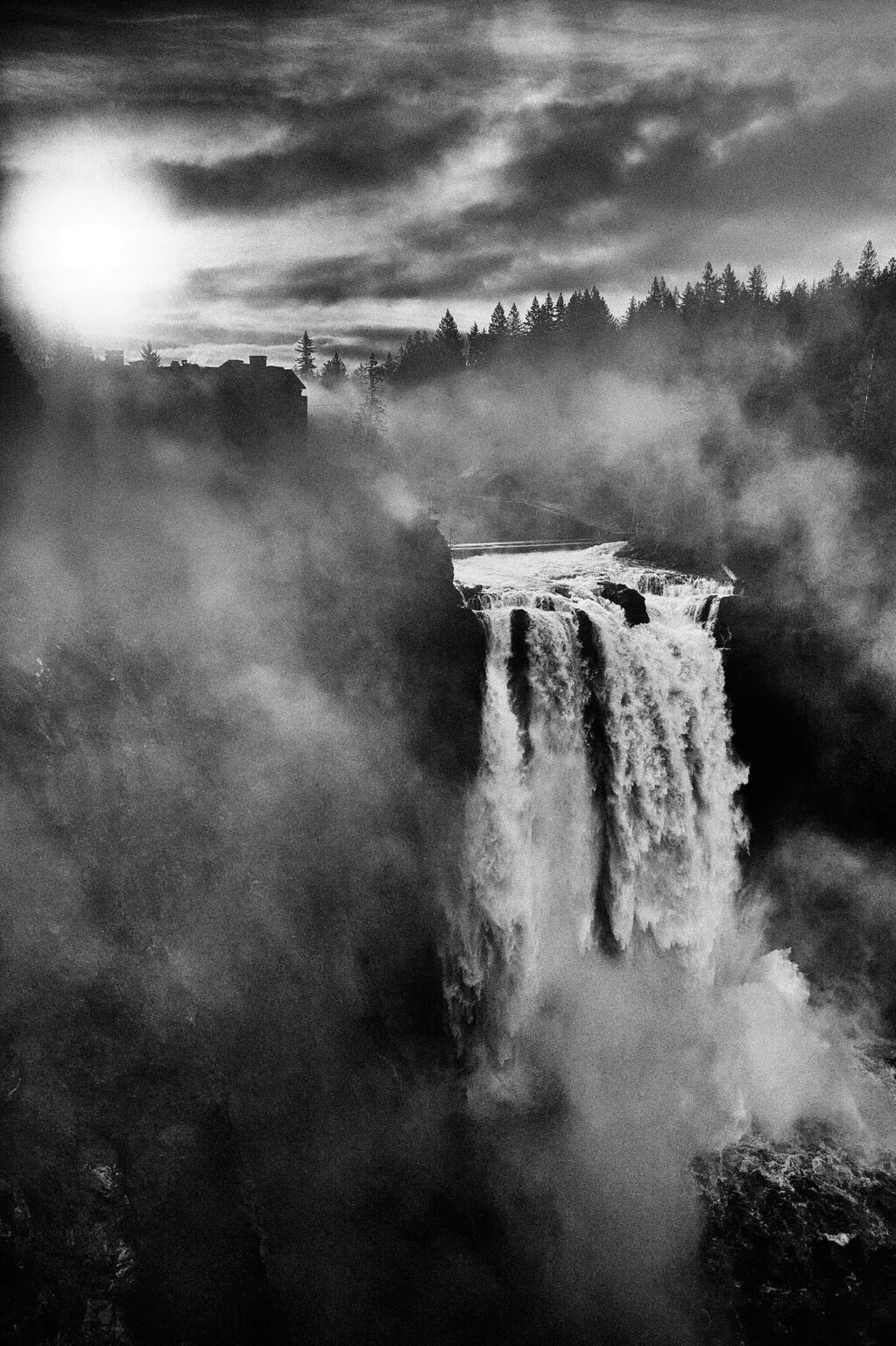Wasserfall im Nebel unter dramatischem Himmel, schwarzweiß