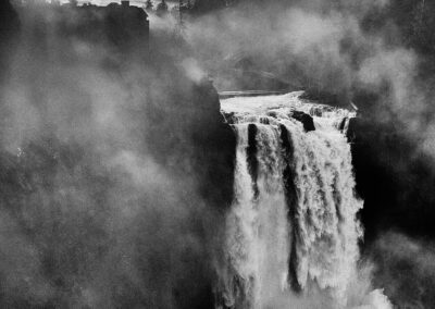 Wasserfall im Nebel unter dramatischem Himmel, schwarzweiß