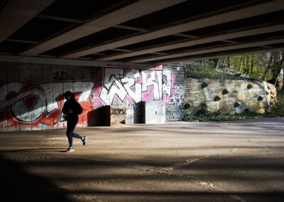 Jogger unter einer Brücke vor einer Graffitiwand