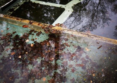 Herbstlaub in einem leeren Brunnenbecken mit Spiegelung