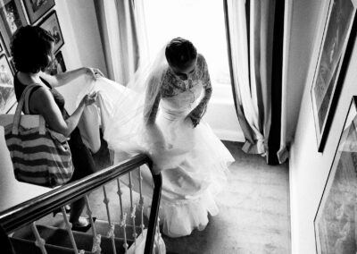 Braut geht mit ihrem Kleid die Treppe hinunter, von oben fotografiert, schwarzweiß – Hochzeit in Hamburg